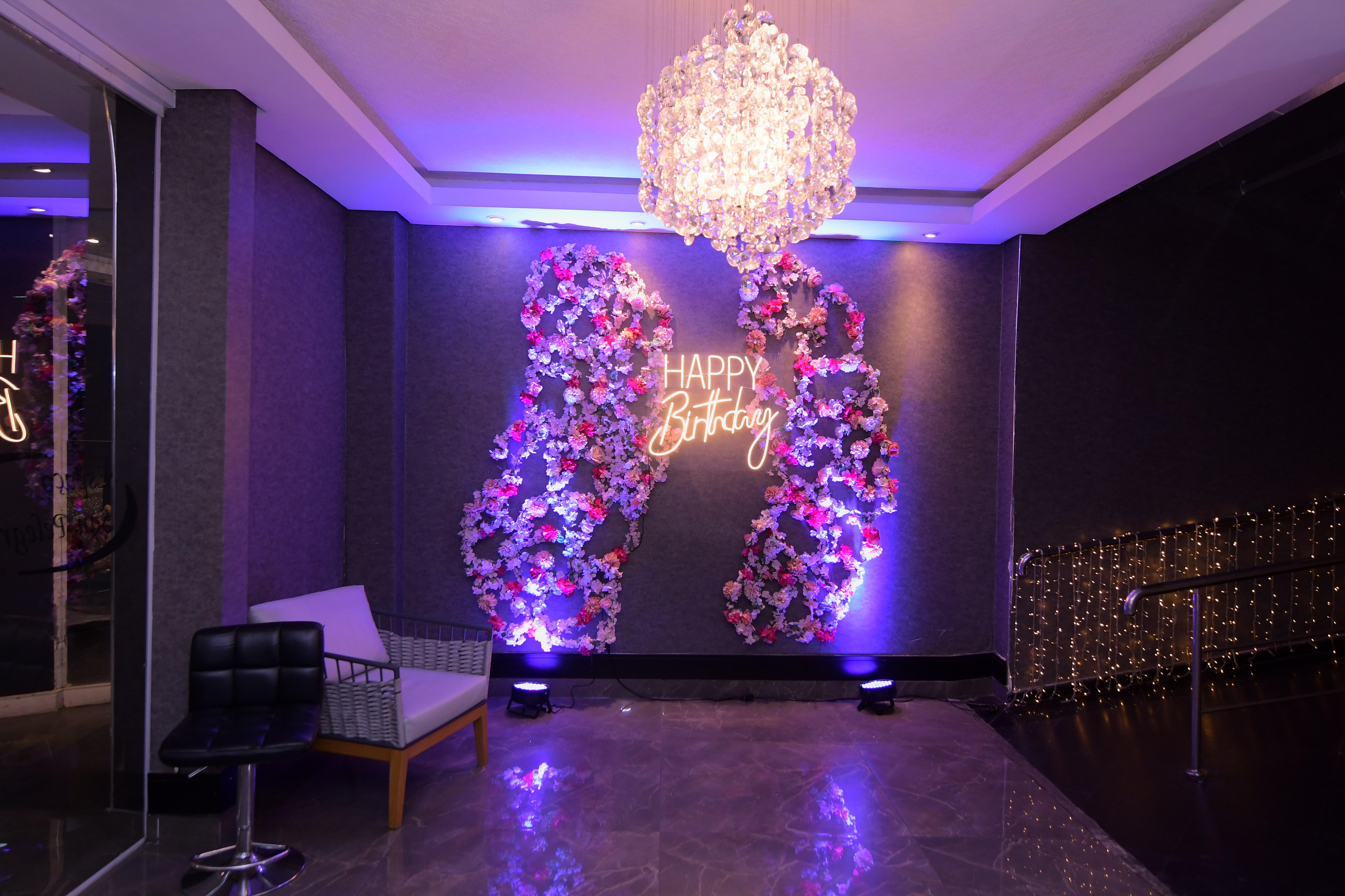 Painel floral do San Pelegrine com letreiro em neon e cortina de luzes douradas