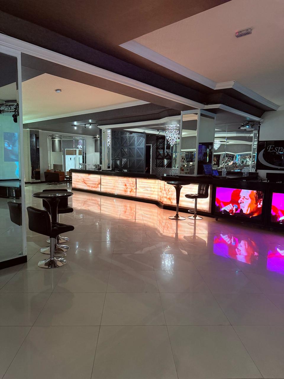 Bar iluminado do Salão Perrie em ônix retroiluminado com banquetas e painéis de vídeo