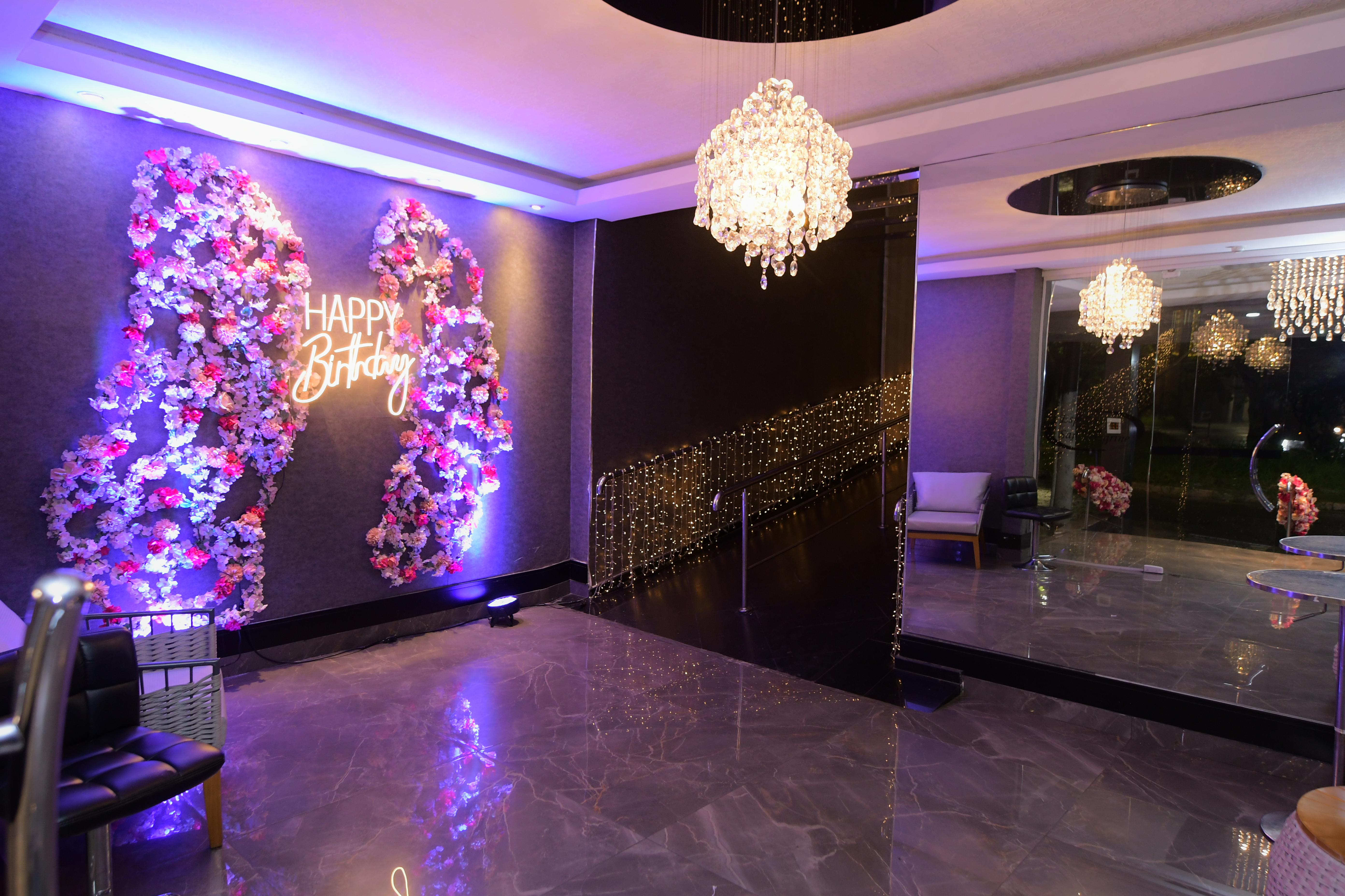 Hall de entrada do San Pelegrine com lustres de cristal, painel floral iluminado e piso de mármore espelhado