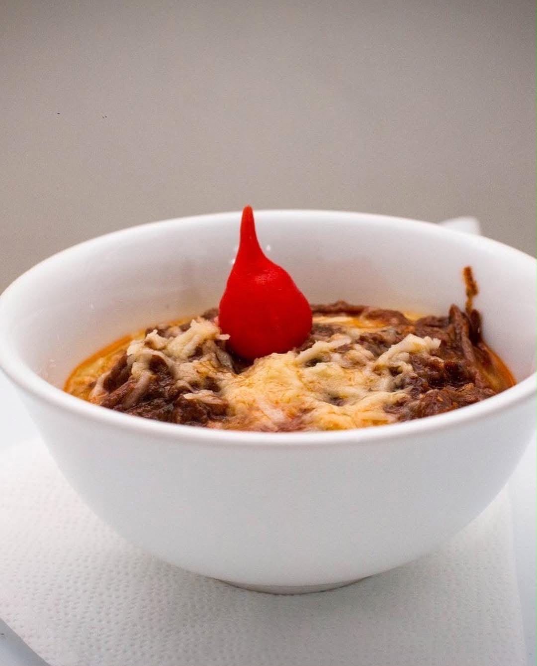 Salada individual com folhas crocantes, tomate e molho da casa servida diante de painel de hortênsias