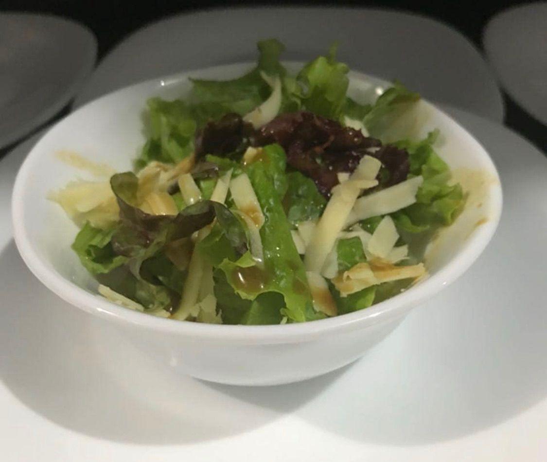 Salada individual de folhas verdes com queijo em lascas, cebola caramelizada e molho da casa em cumbuca branca
